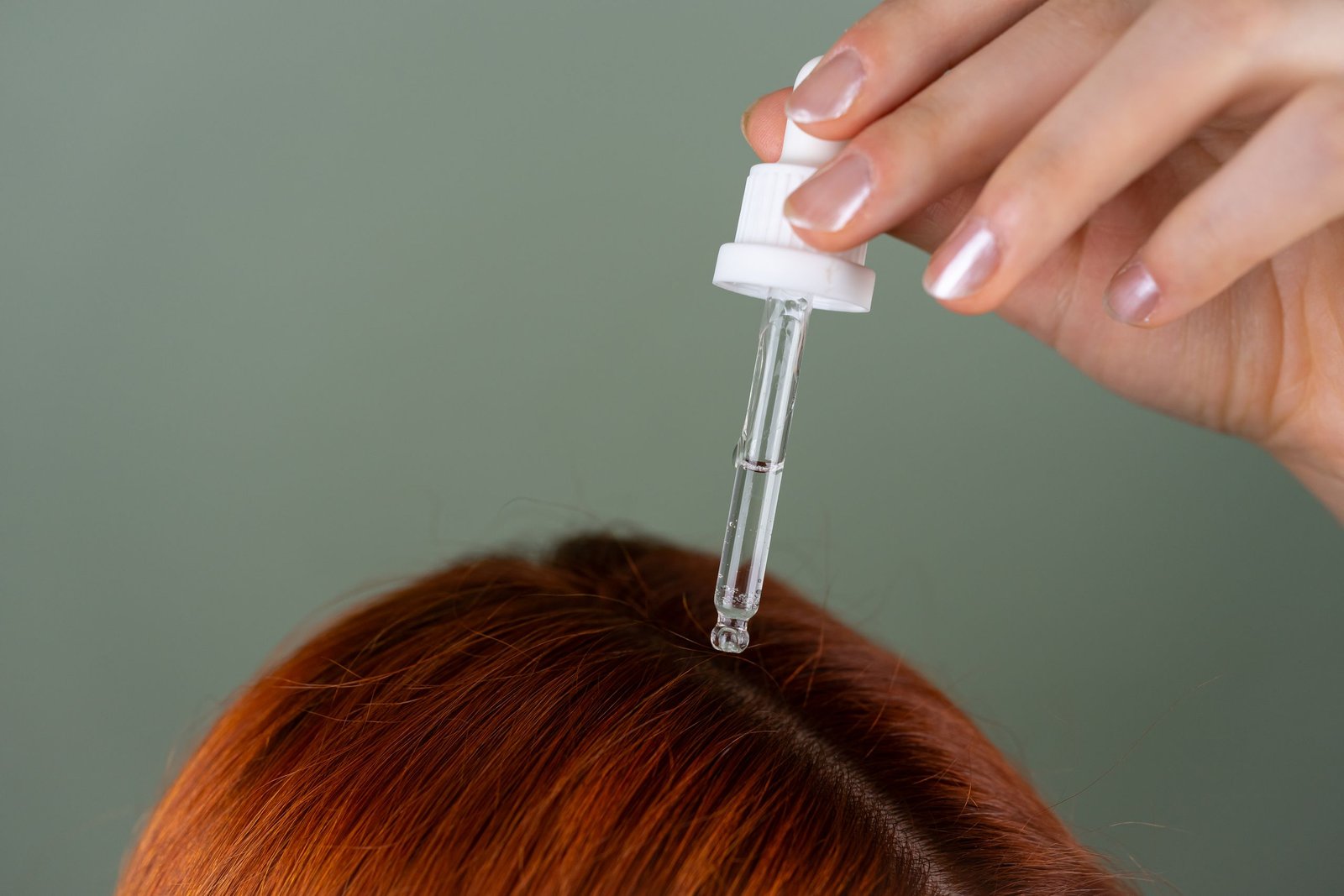 Applying hair serum with a dropper directly to the hair