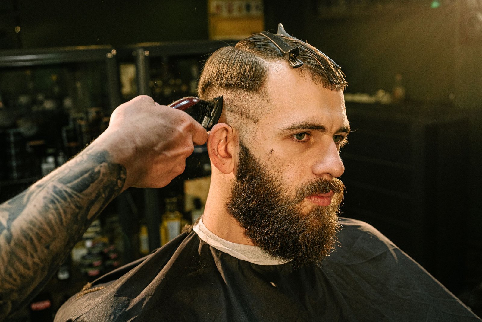 Barber buzzing the sides of a man's hair short for a high and tight haircut