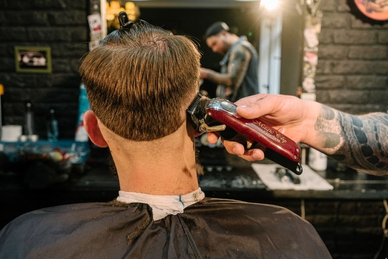 Barber creating a taper fade haircut, blending the sides down to skin