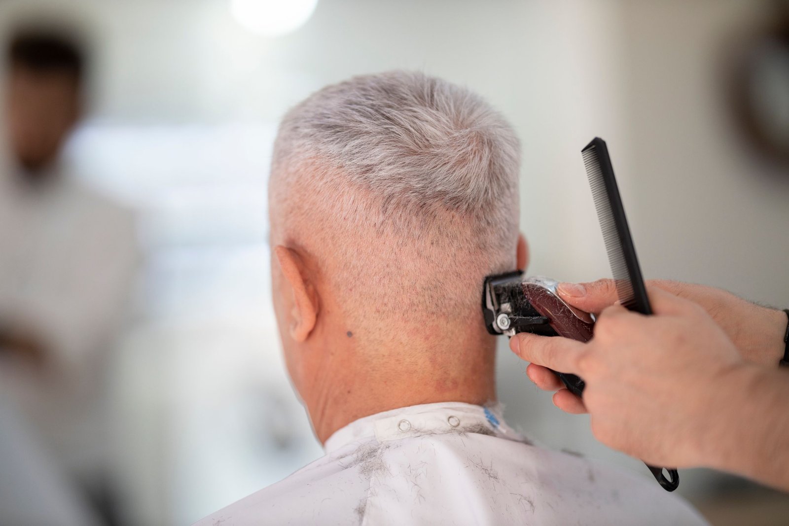 Barber giving an older man a short, low-maintenance buzz cut