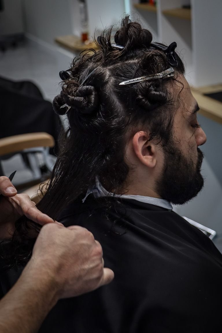Barber styling a man's curly permed hair