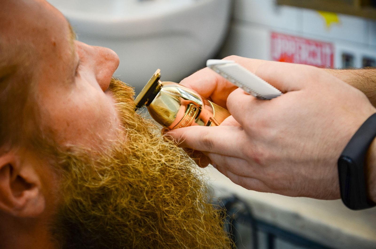 Barber trimming and shaping a man's beard with a razor, showing the kind of regular professional grooming that keeps a beard style sharp.