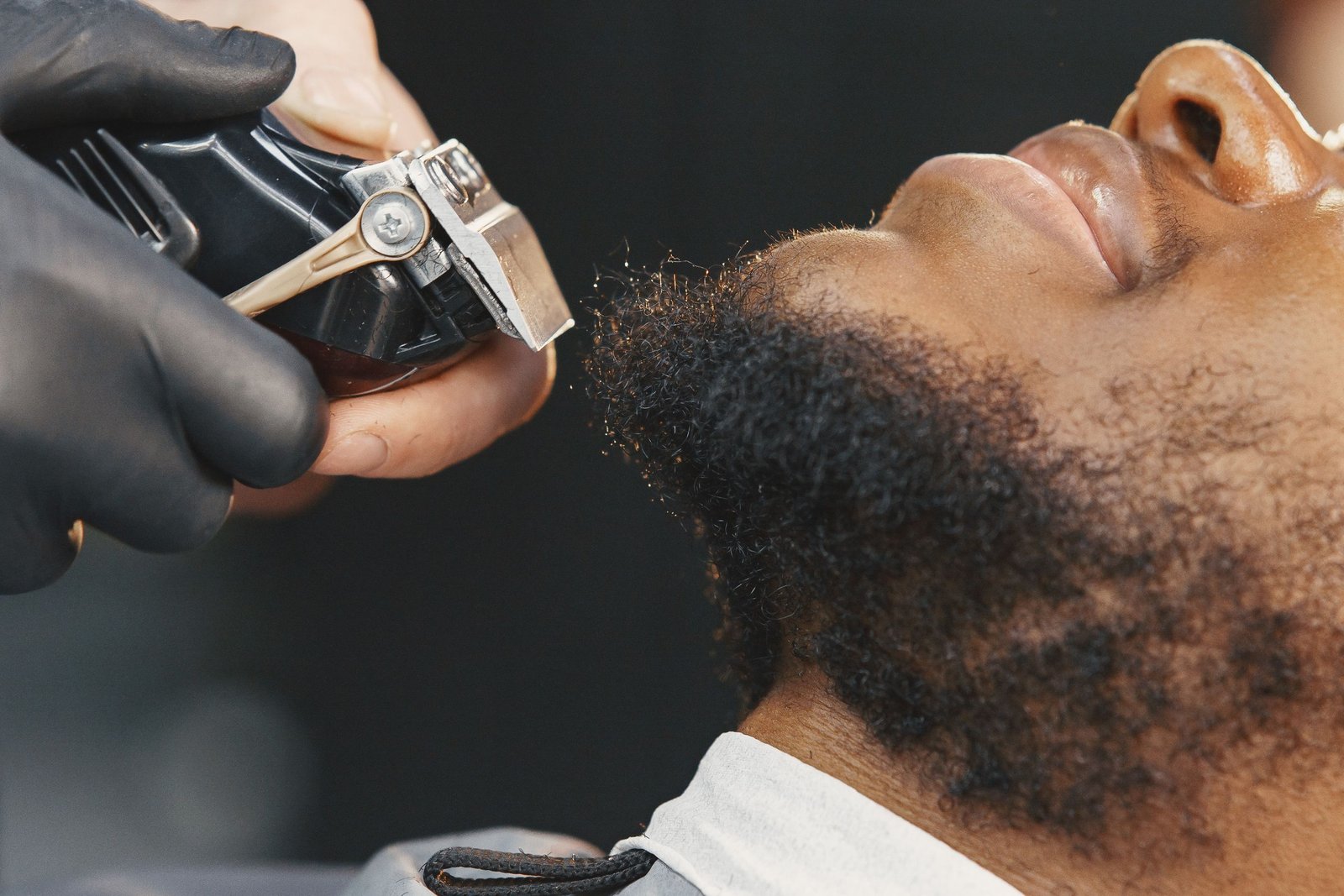 Barber using clippers to shape a short boxed beard