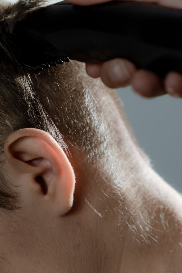 Close-up of a hair clipper cutting hair, showing the blade making contact with the scalp during a haircut.k