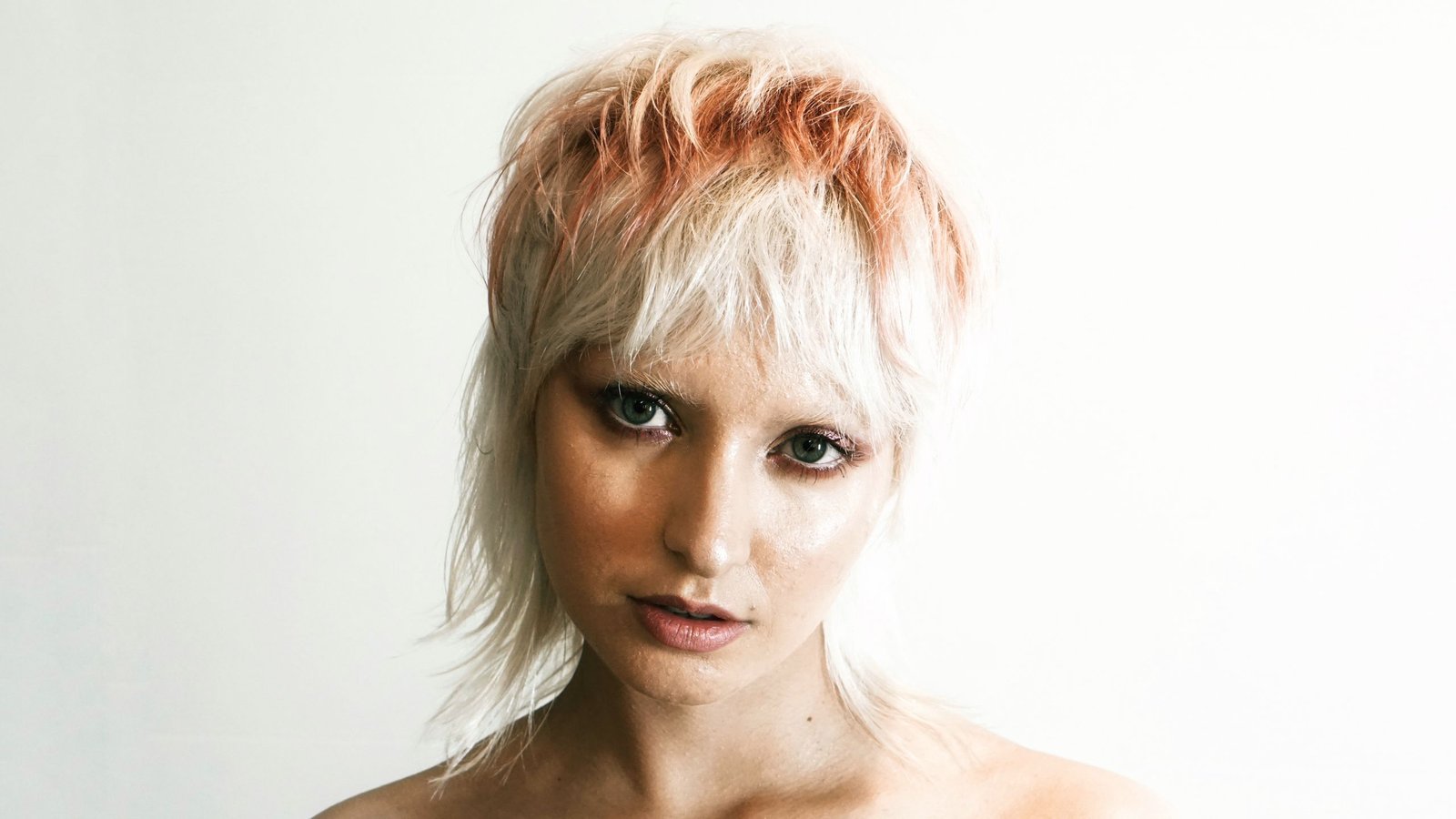 Close-up of a pixie haircut with light face-framing highlights.