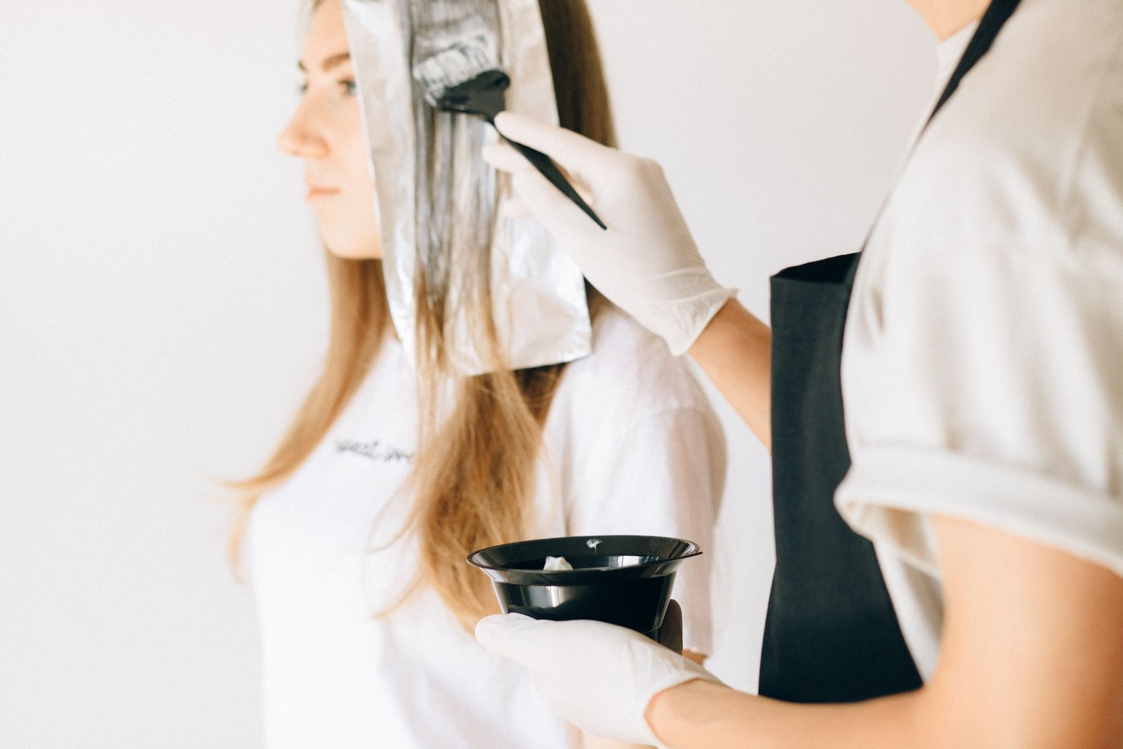 Hairdresser applying curly hair color using a foil highlighting technique
