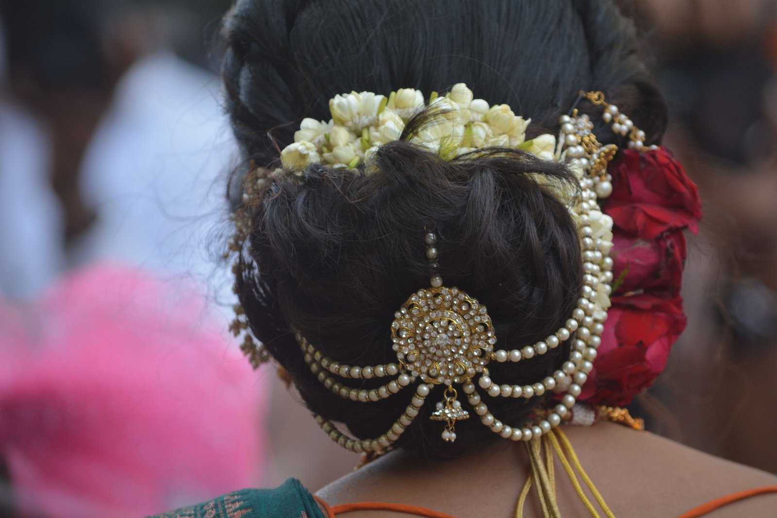 Indian bride's bun hairstyle adorned with jasmine flowers, pearls, and gold ornaments