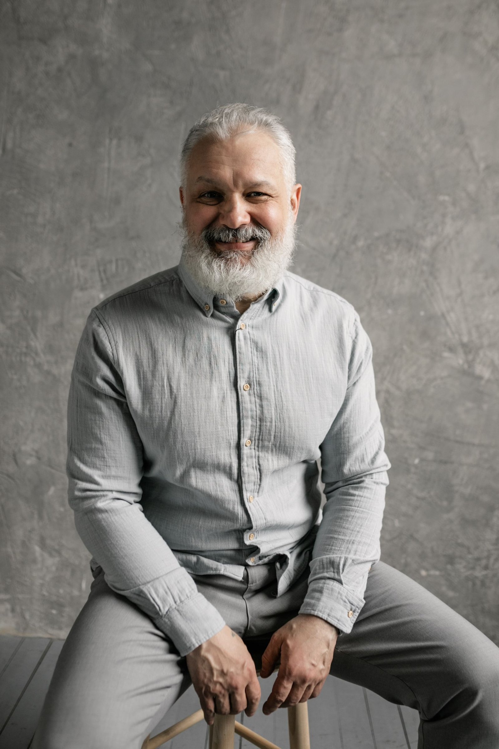 Smiling older man with a full gray beard and short gray hair, an example of a classic hairstyle and beard pairing for mature men.