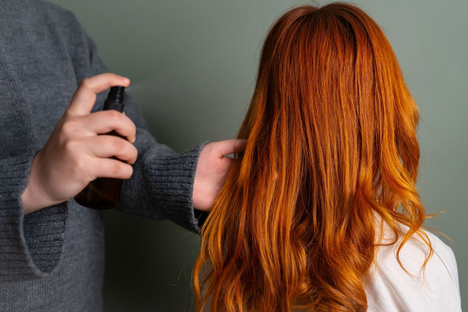 Spraying a leave-in conditioner onto hair to seal in moisture between wash days