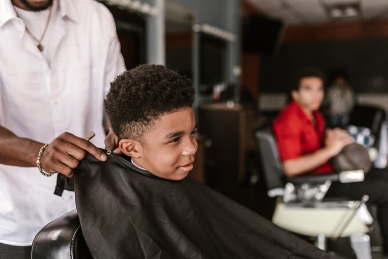 Toddler boy smiling during a gentle first haircut at the barbershop