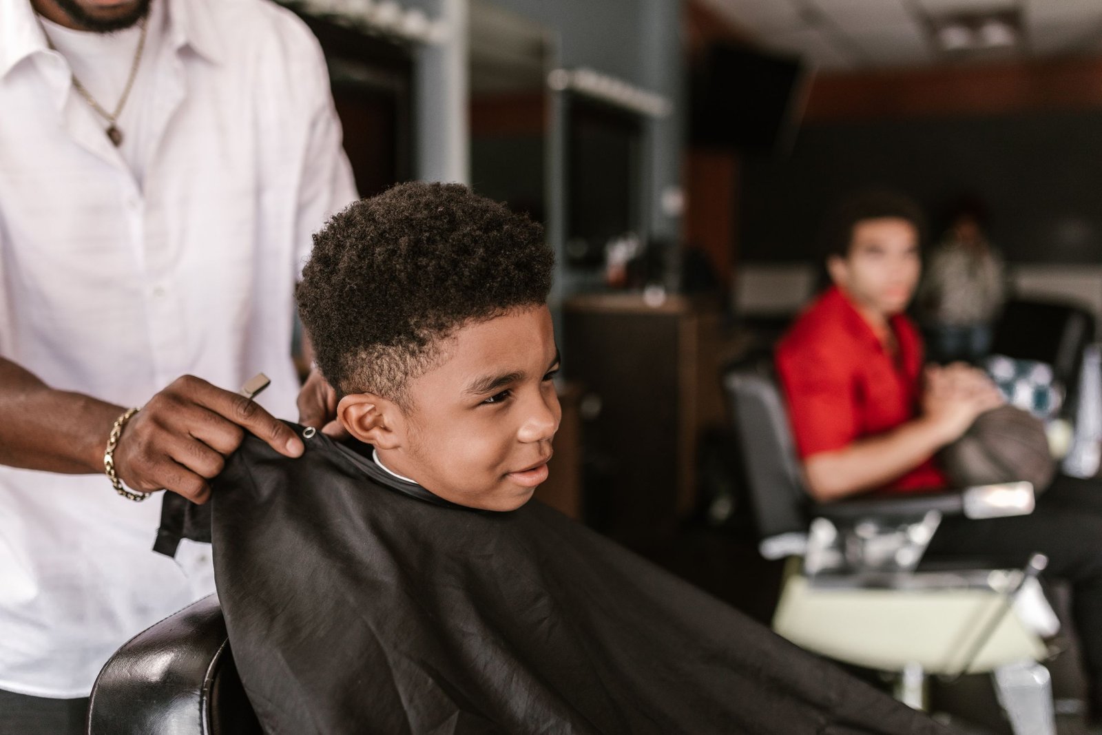 Toddler boy smiling during a gentle first haircut at the barbershop