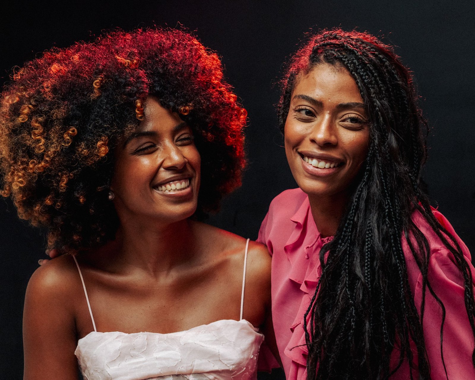 Two women showing different natural hair textures and curl patterns
