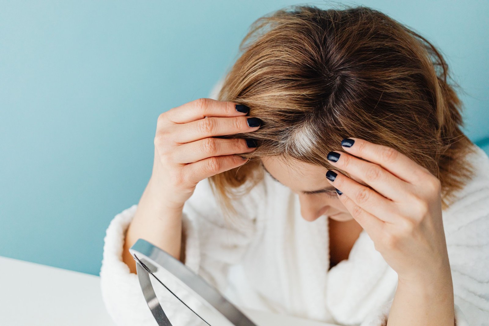Woman checking her hair part in the mirror to look for signs of thinning