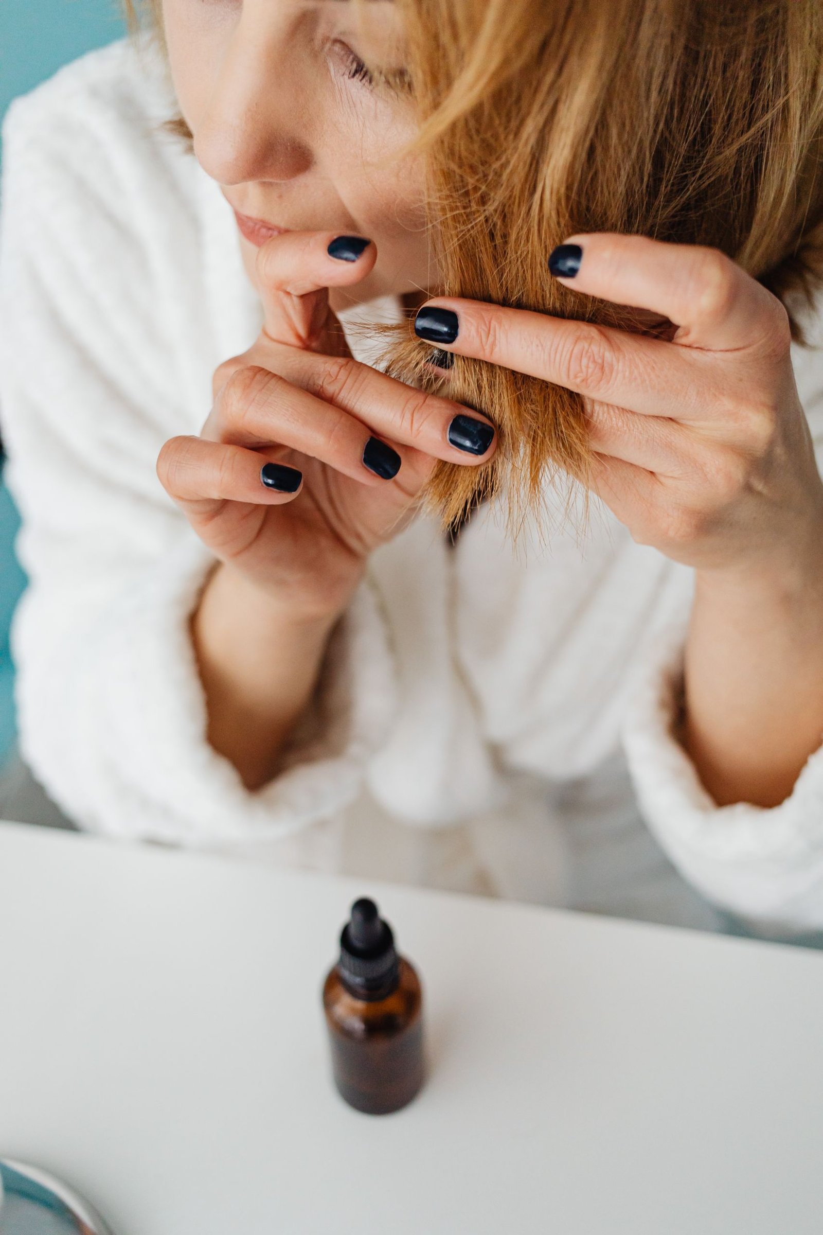 Woman closely examining a strand of her hair to check its texture