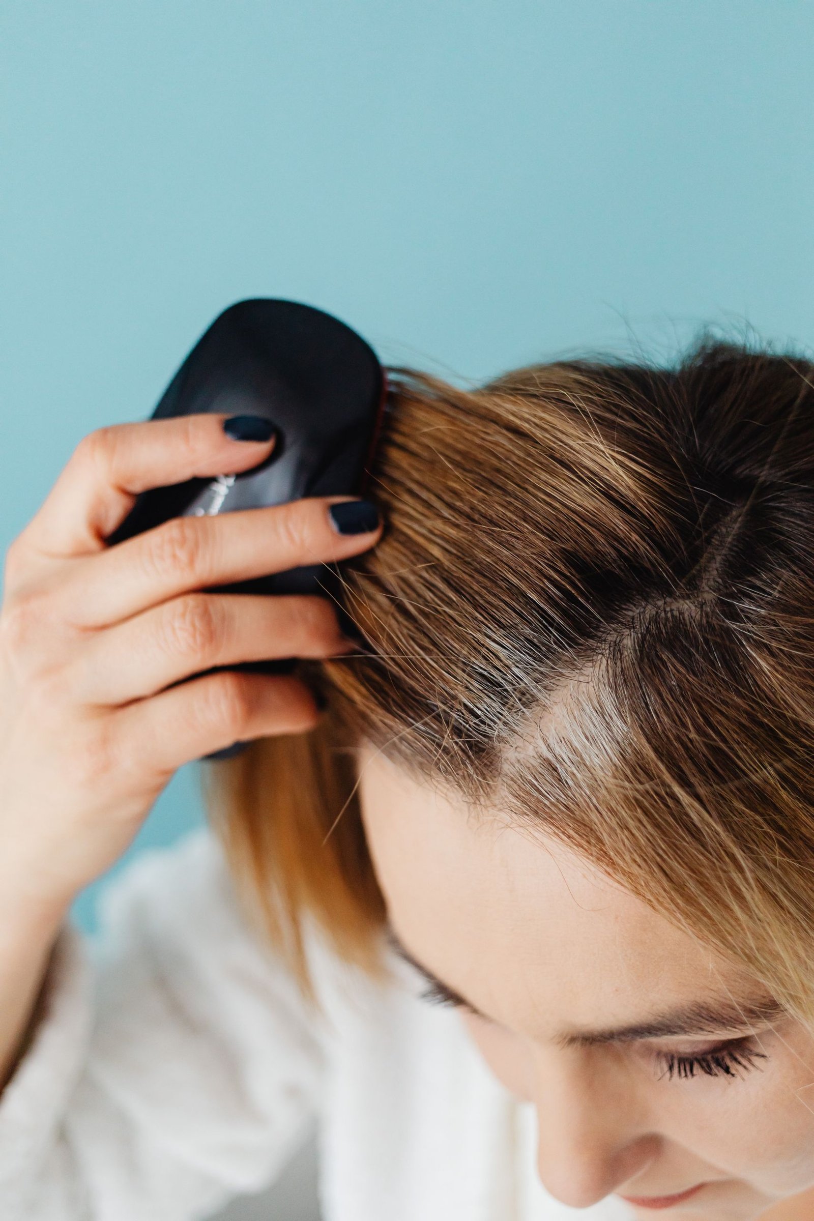 Woman gently brushing her hair with a soft-bristle brush to reduce breakage
