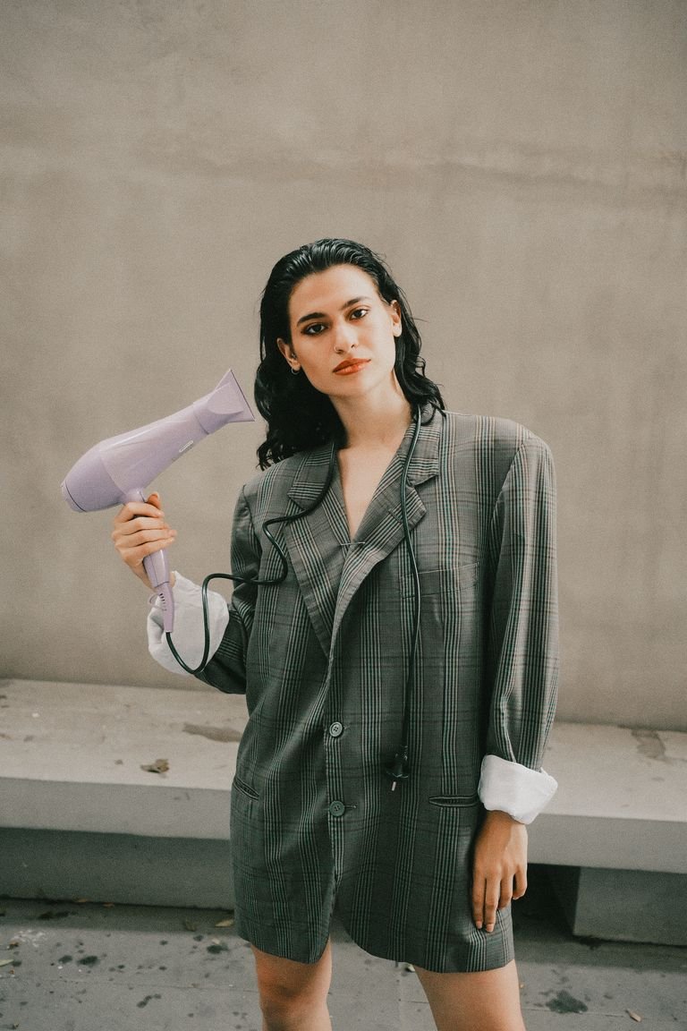 Woman styling retro-inspired 90s hair with a blow dryer