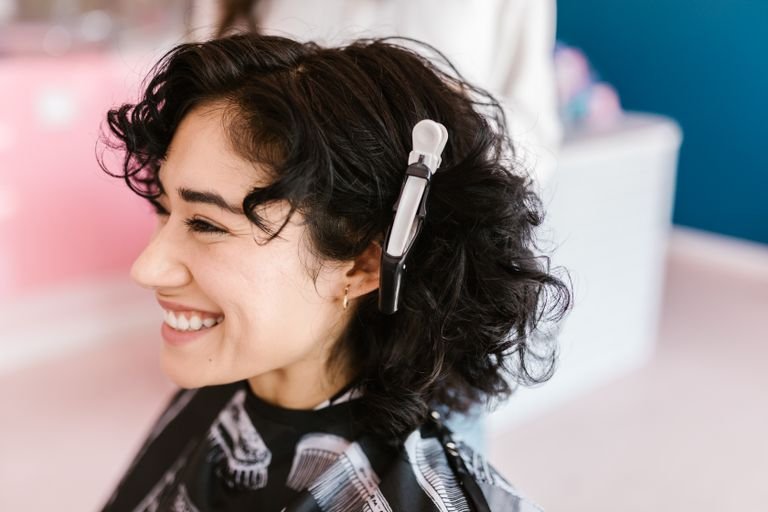 Woman with a layered curly haircut featuring soft face-framing pieces