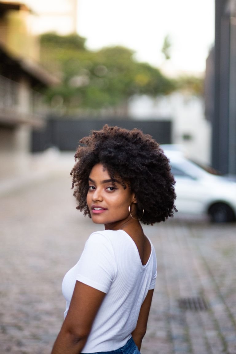 Woman with defined 4A natural curly coily hair looking over her shoulder