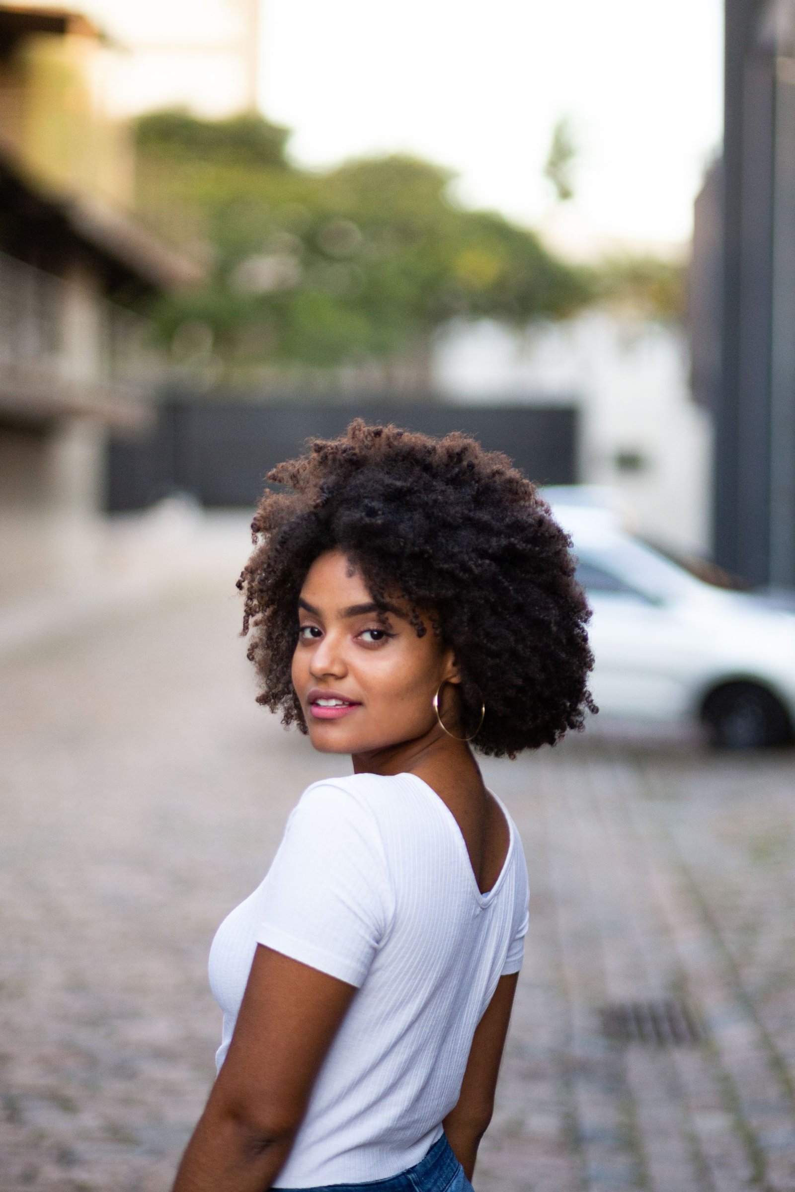 Woman with defined 4A natural curly coily hair looking over her shoulder