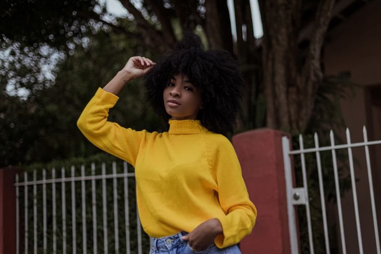 Woman with natural 4C afro hair texture touching her curls outdoors