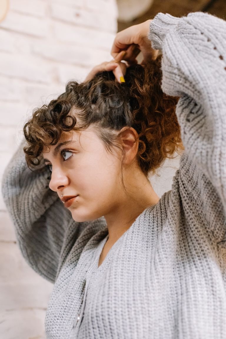 Woman with thick curly hair styling it into an easy everyday updo