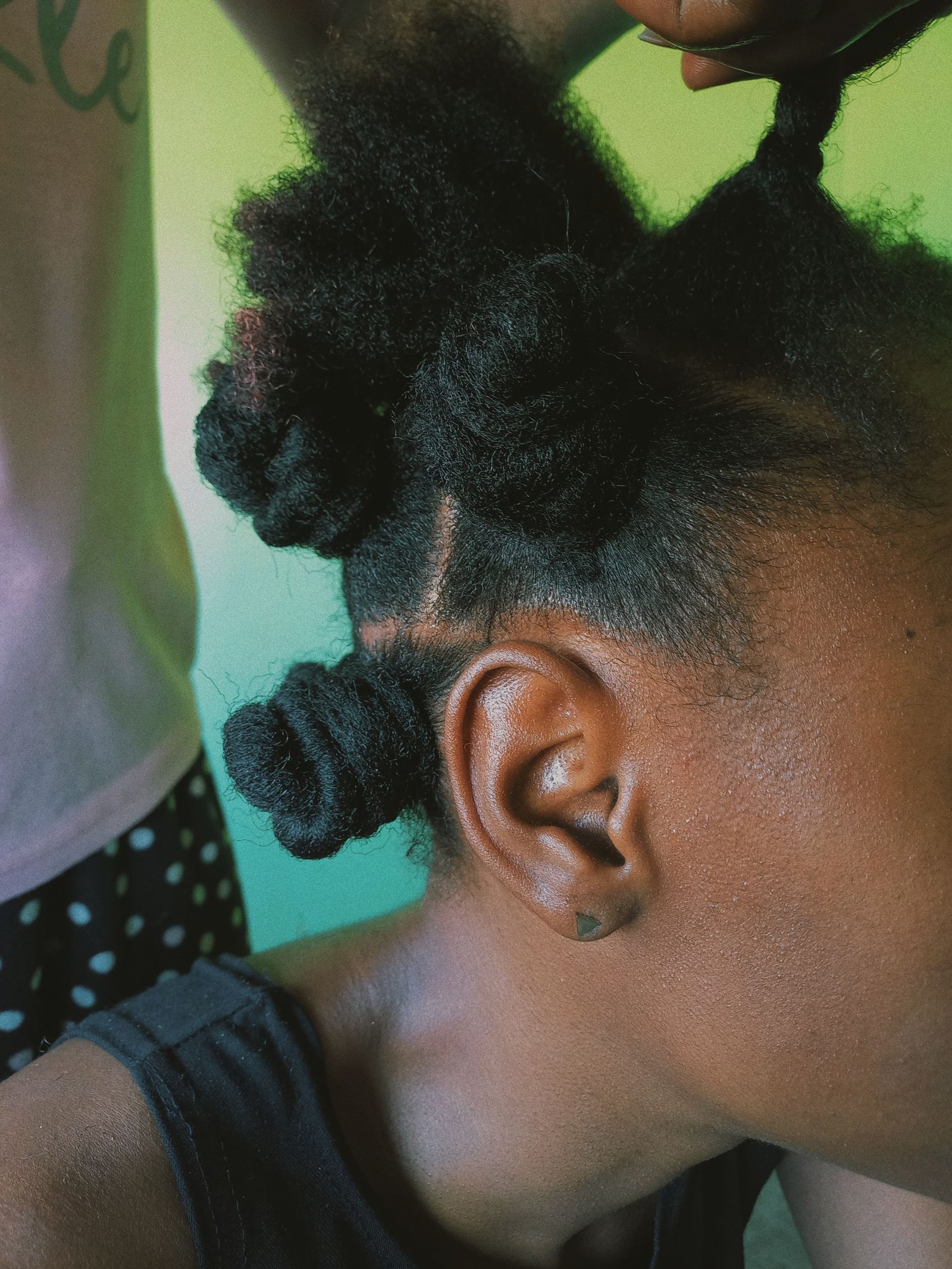 Young child getting bantu knots styled in her natural hair