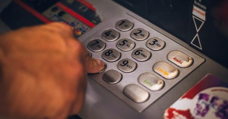 Person pressing a button on an ATM keypad to check a card balance