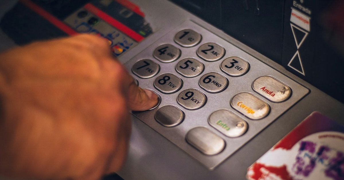 Person pressing a button on an ATM keypad to check a card balance