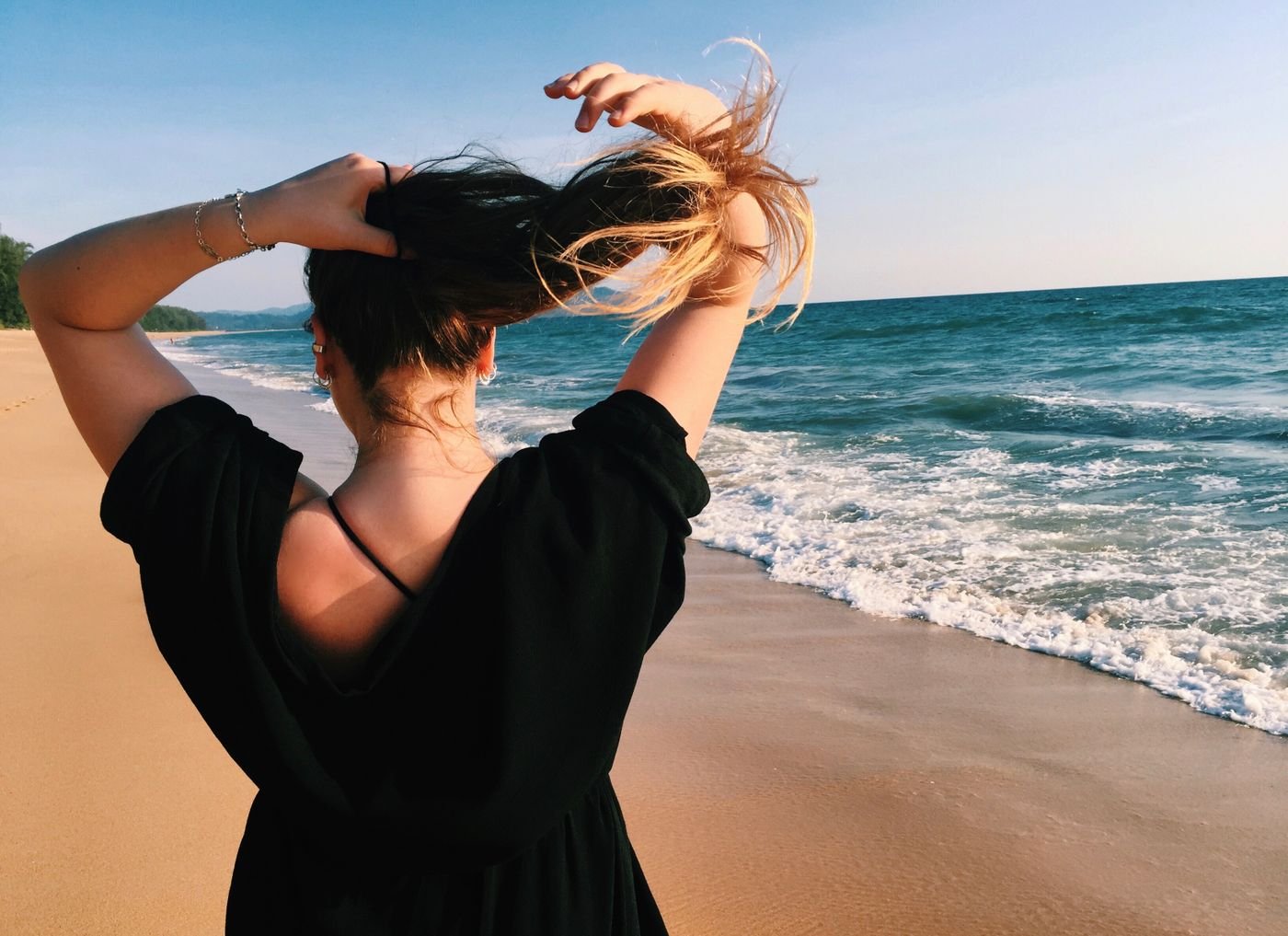 Woman on a beach lifting her hair in the breeze