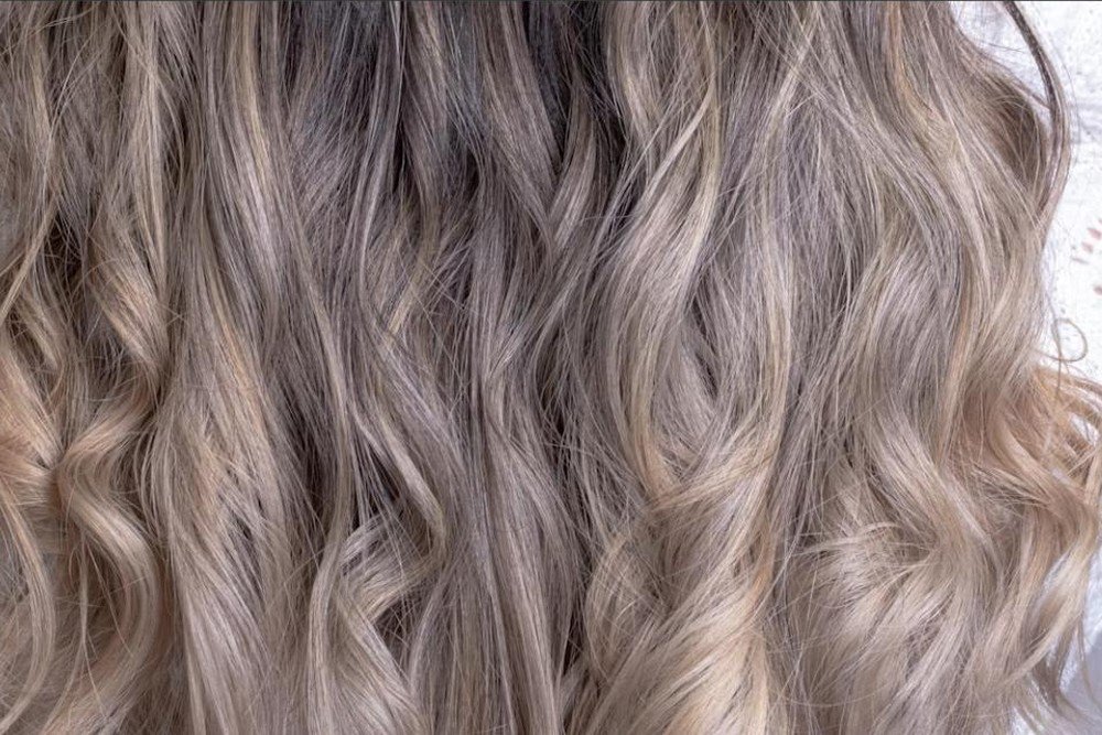 Close-up of wavy blonde balayage hair showing seamless root-to-end color blending