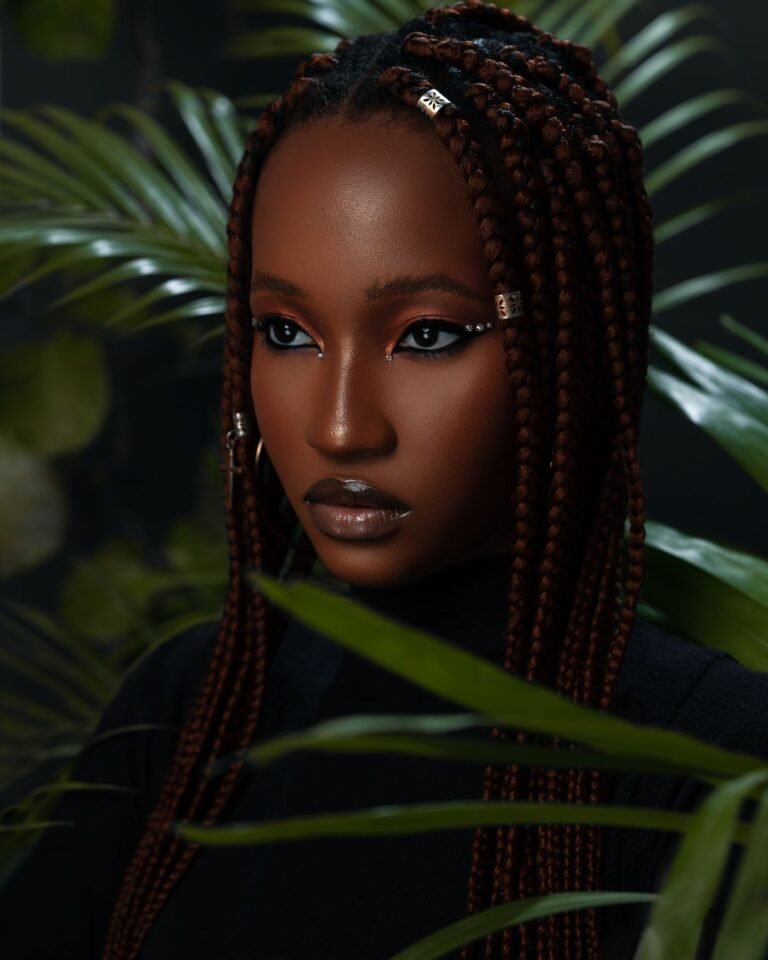 Portrait of a woman with box braids surrounded by foliage