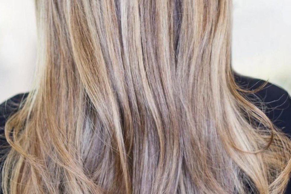 Close-up of brown hair with soft blonde highlight pieces blended through the lengths