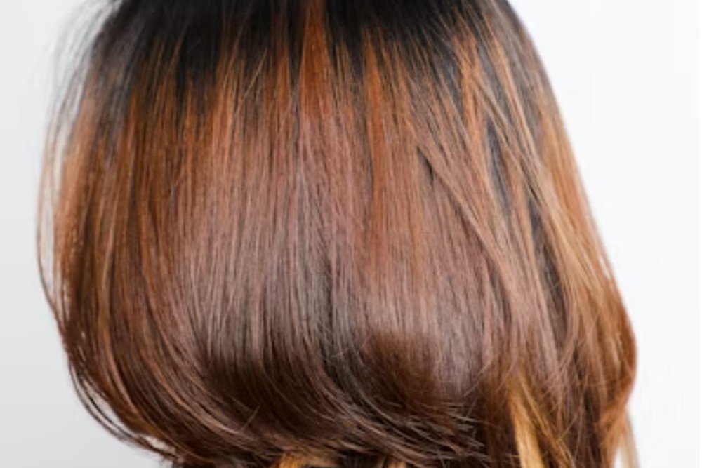 Close-up of dark brown hair with copper and red highlights melting through the roots