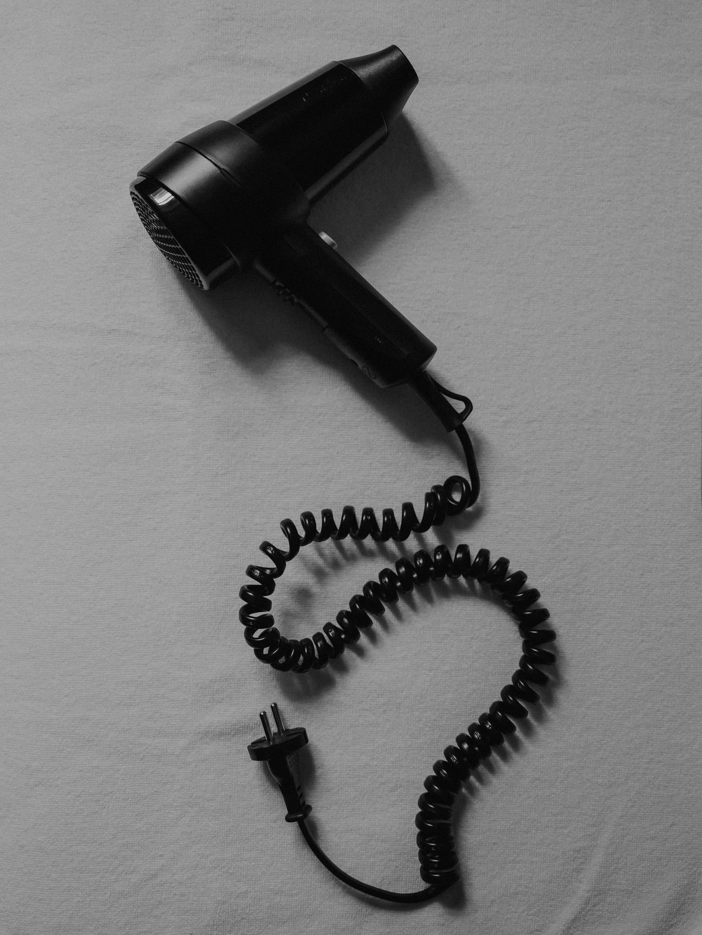Minimalist black hair dryer with coiled cord flat lay