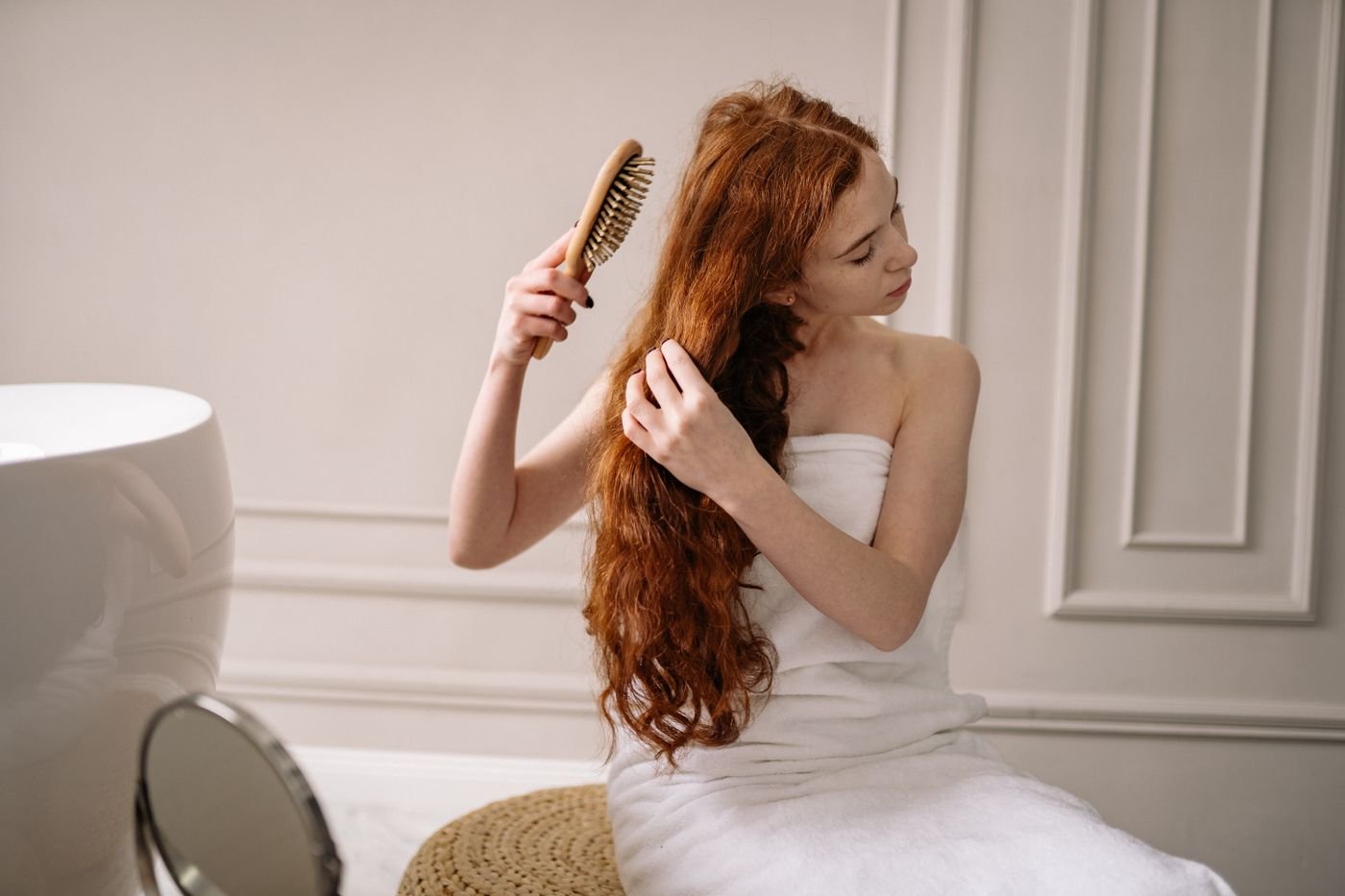 Woman with long hair wrapped in a towel combing her hair