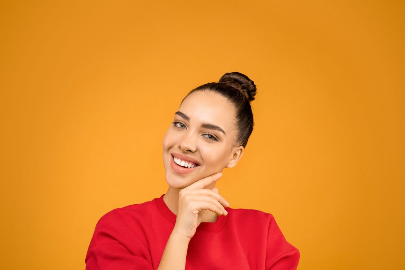 Young woman with a stylish bun posing confidently indoors