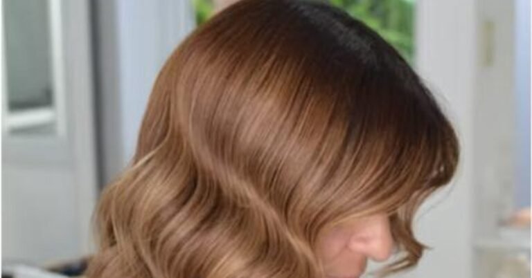 Woman with warm copper-red hair styled in loose waves, showing dimensional balayage highlights