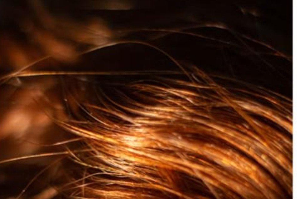 Close-up of red hair with warm golden-copper highlights catching the light