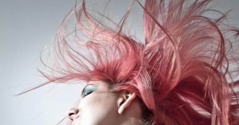 Dynamic red-violet hair color with magenta and plum tones blown in motion